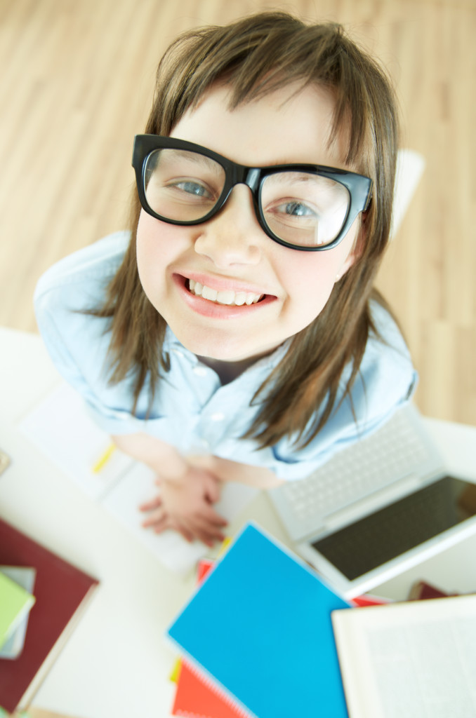 Vertical portrait of a funny school girl wearing nerdy eyeglasses