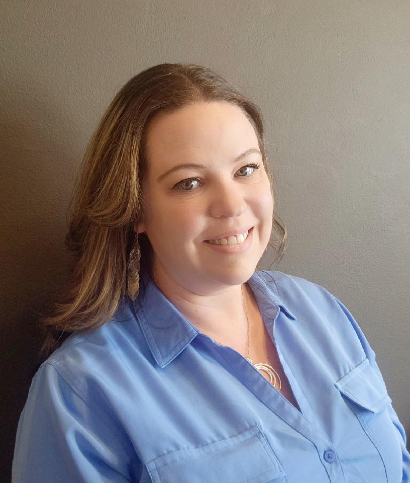 Smiling woman in blue shirt with long hair to shoulders